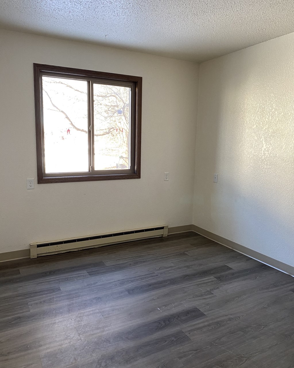 an empty room with wood floors and a window