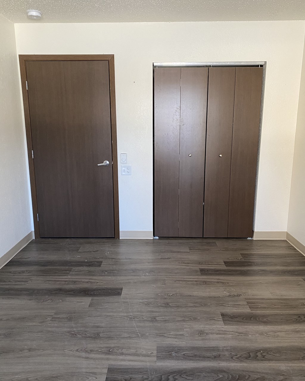 an empty room with two doors and a wooden floor