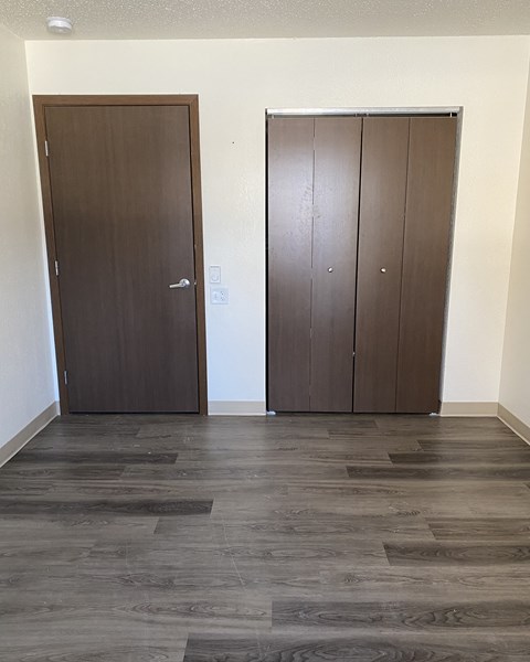 an empty room with two doors and a wooden floor