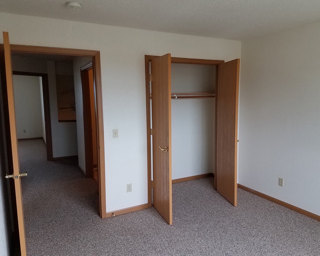 an empty bedroom with three doors and a closet