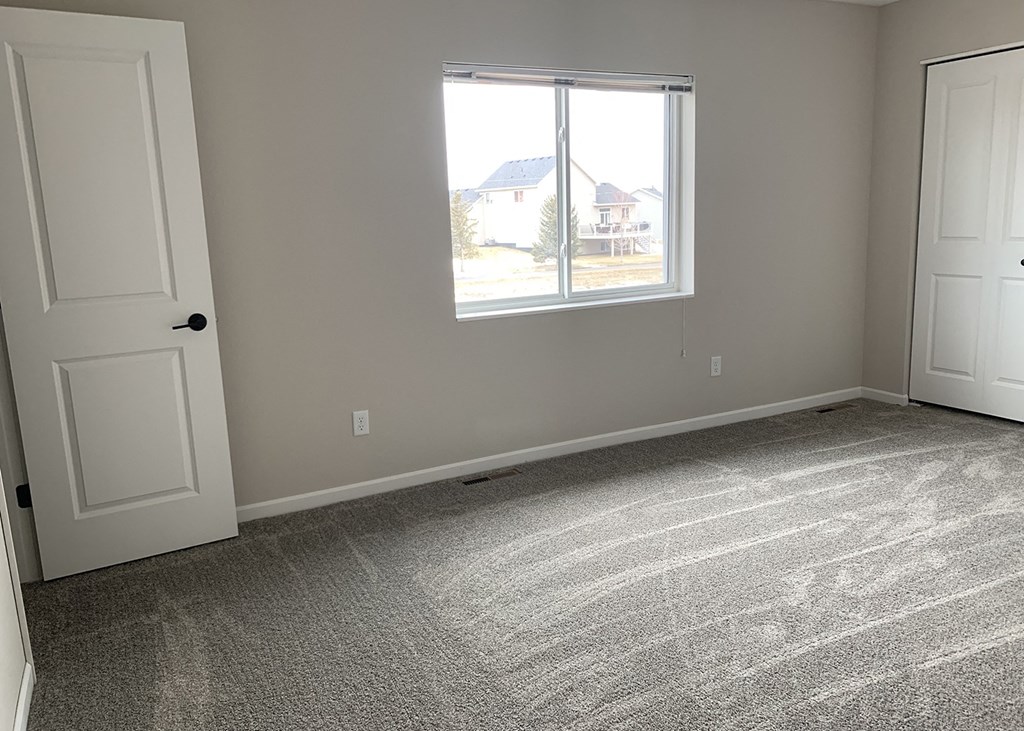 an empty bedroom with two doors and a window
