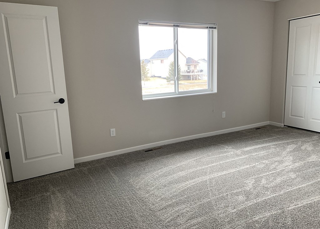 an empty bedroom with two doors and a window
