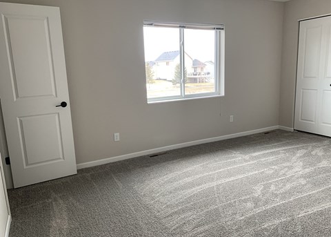 an empty bedroom with two doors and a window