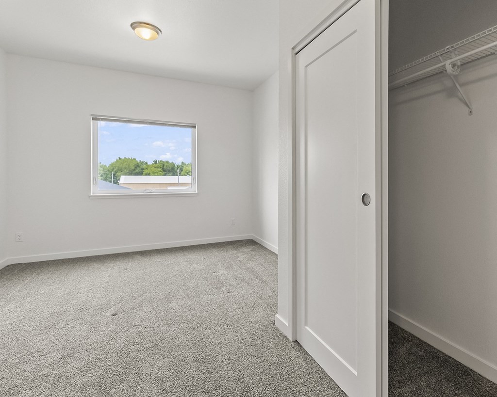 an empty bedroom with a window and a closet