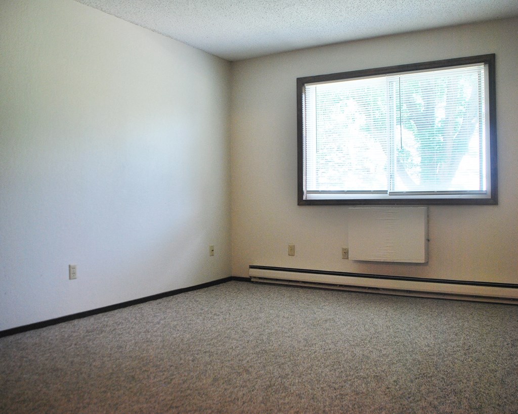 an empty room with a window and a white wall