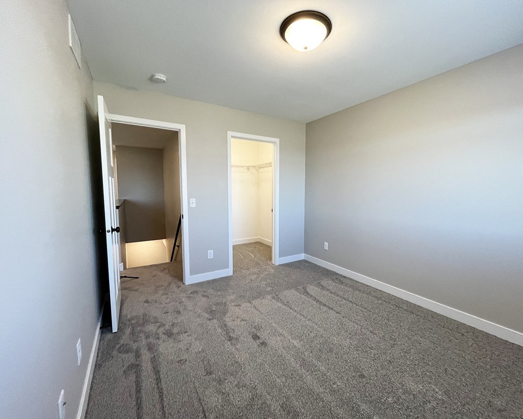 an empty living room with carpet and a door to a closet