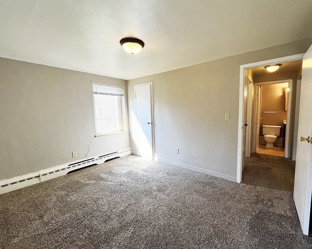 an empty living room with carpet and a door to a bathroom