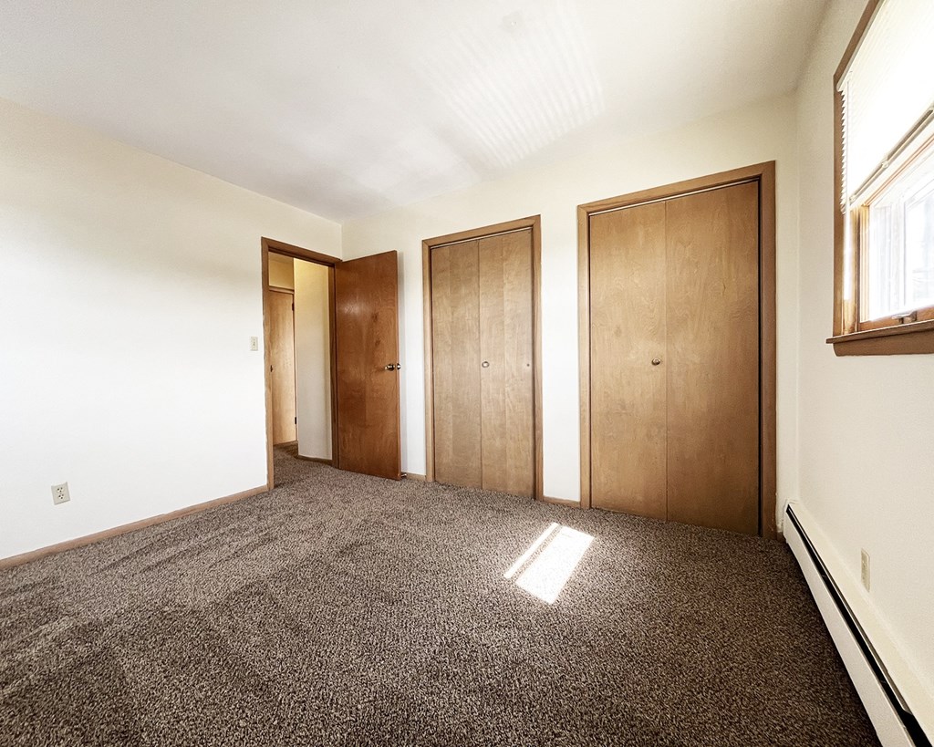 an empty room with three doors and a carpeted floor
