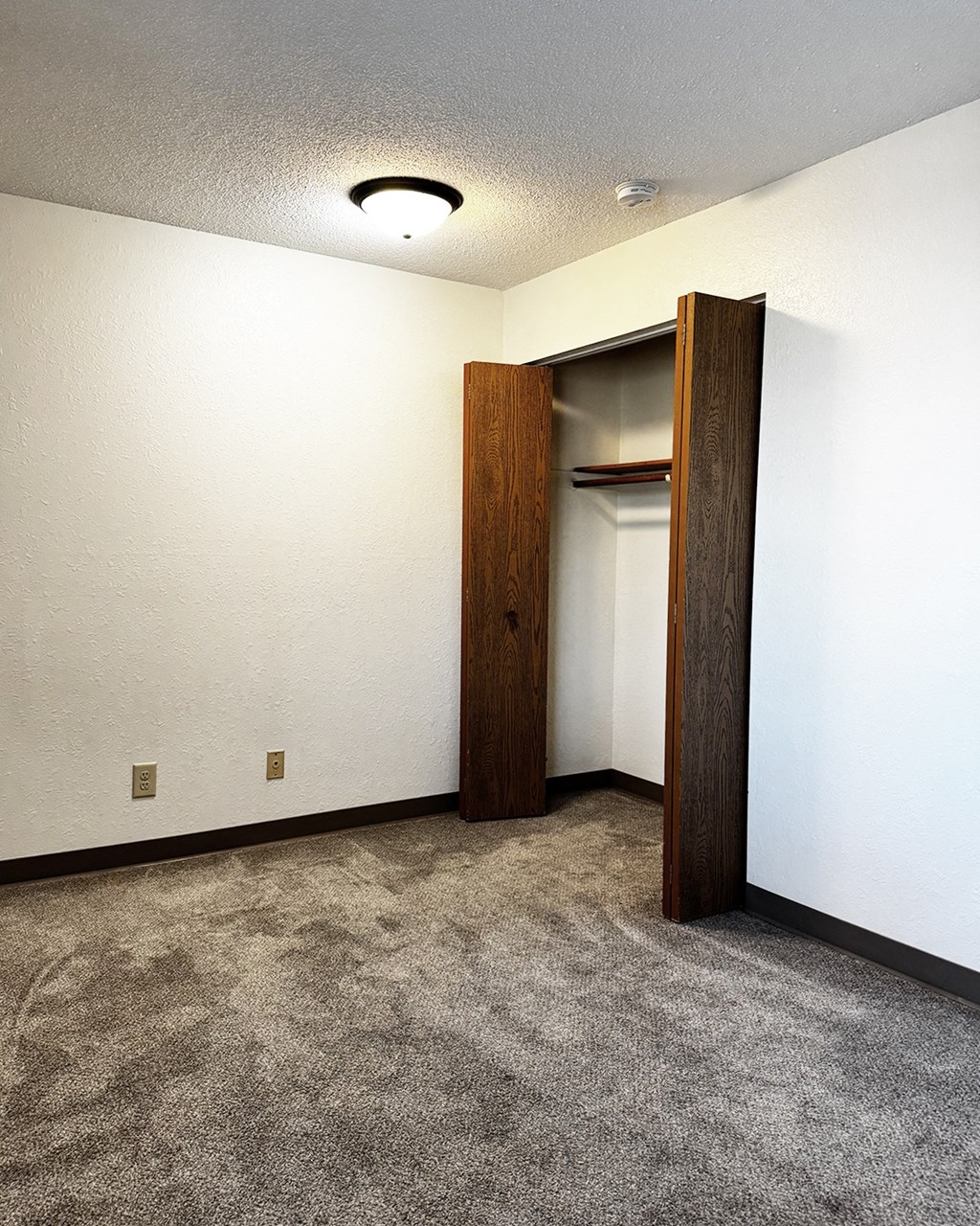 A room with a carpeted floor and a wooden door.