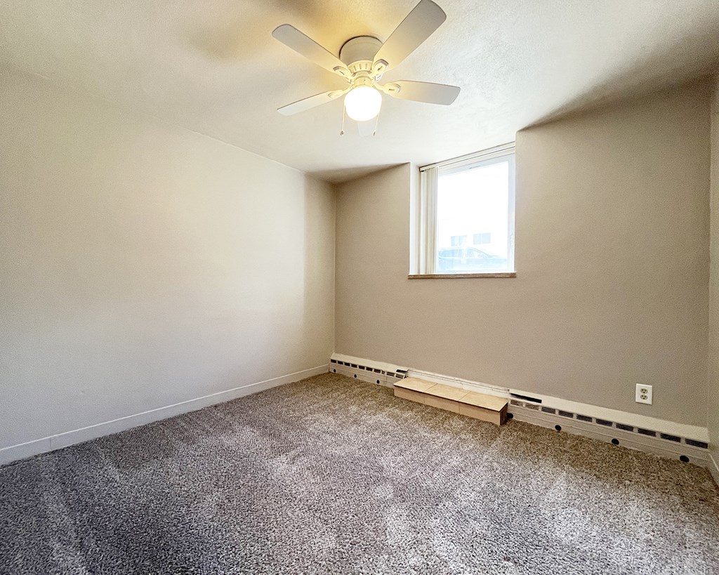 an empty room with a ceiling fan and a window