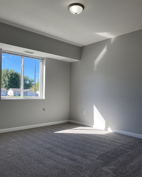 A room with a large window and a carpeted floor.