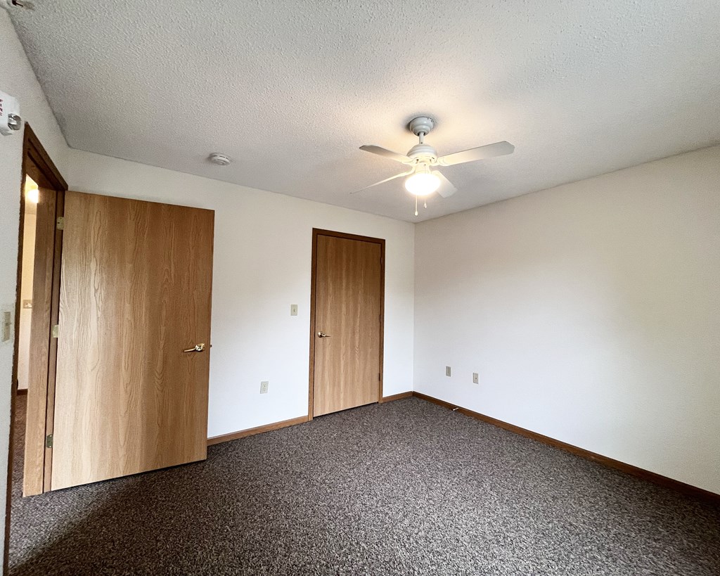 A room with a ceiling fan and carpeted floor.