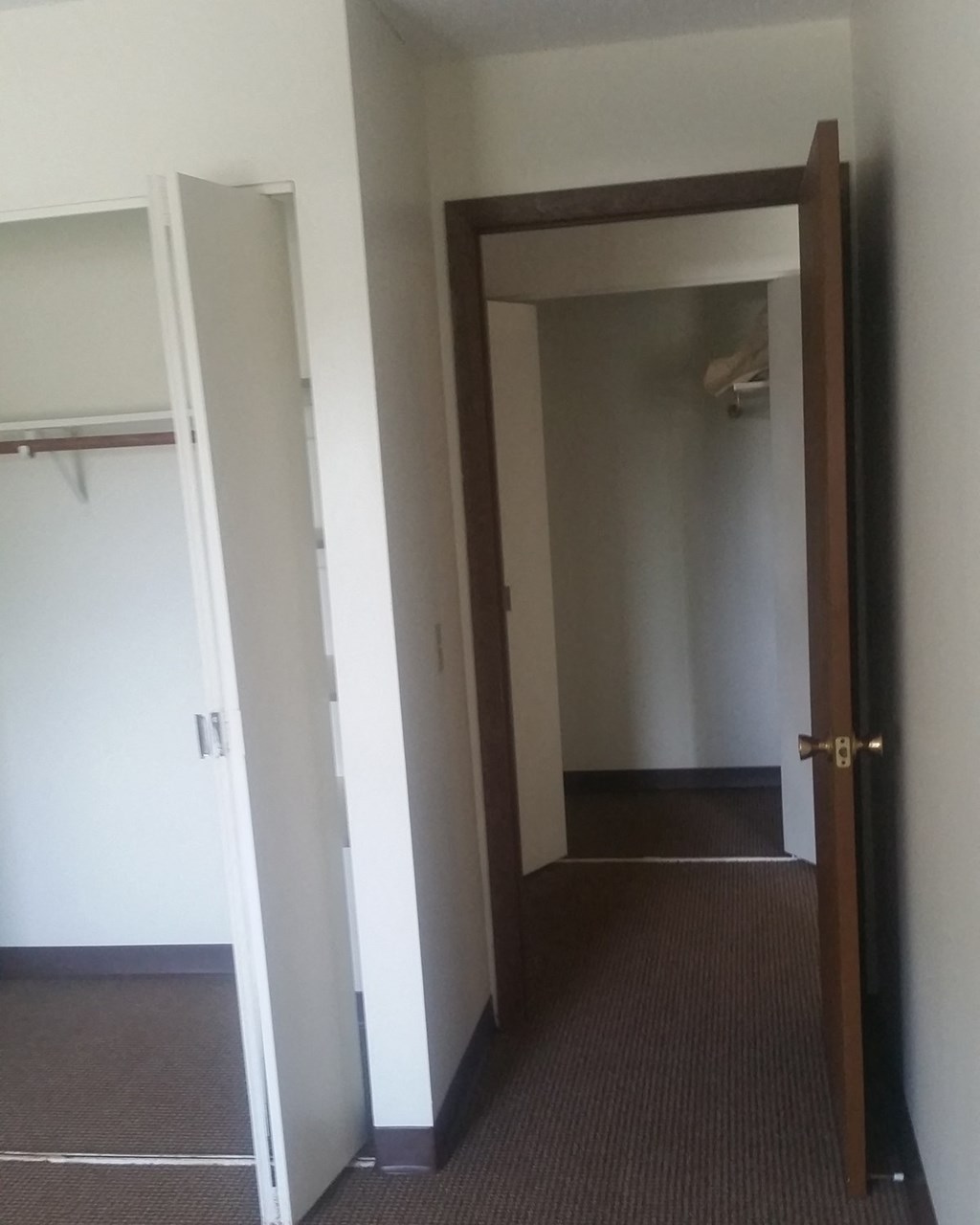 an empty room with a door open to a hallway and a closet