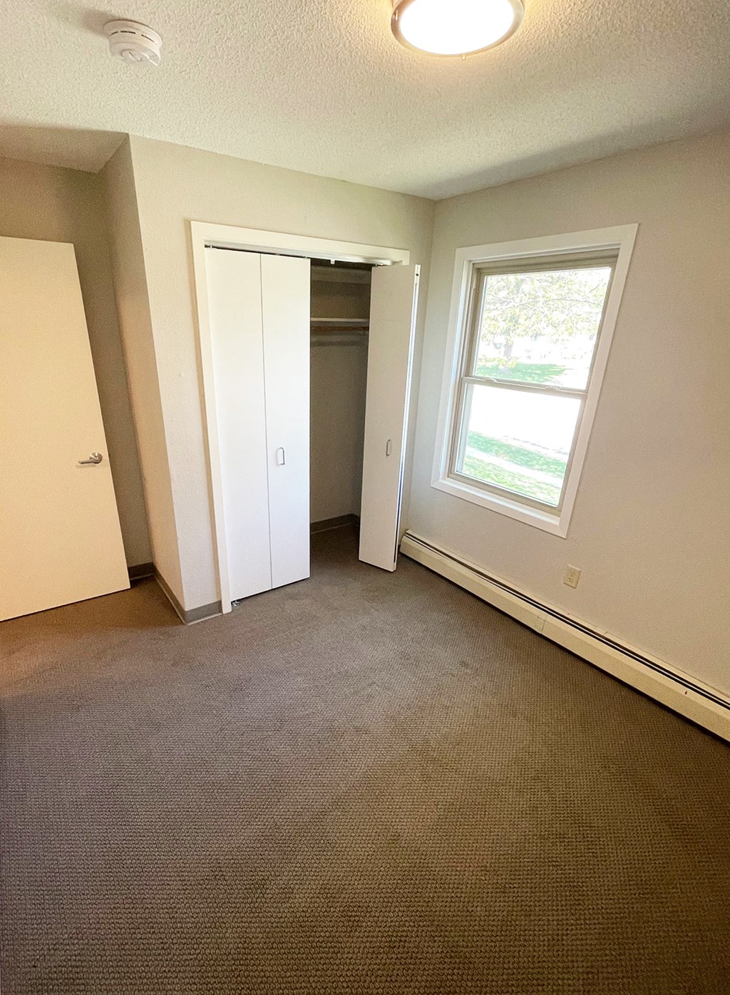 an empty bedroom with a window and a closet