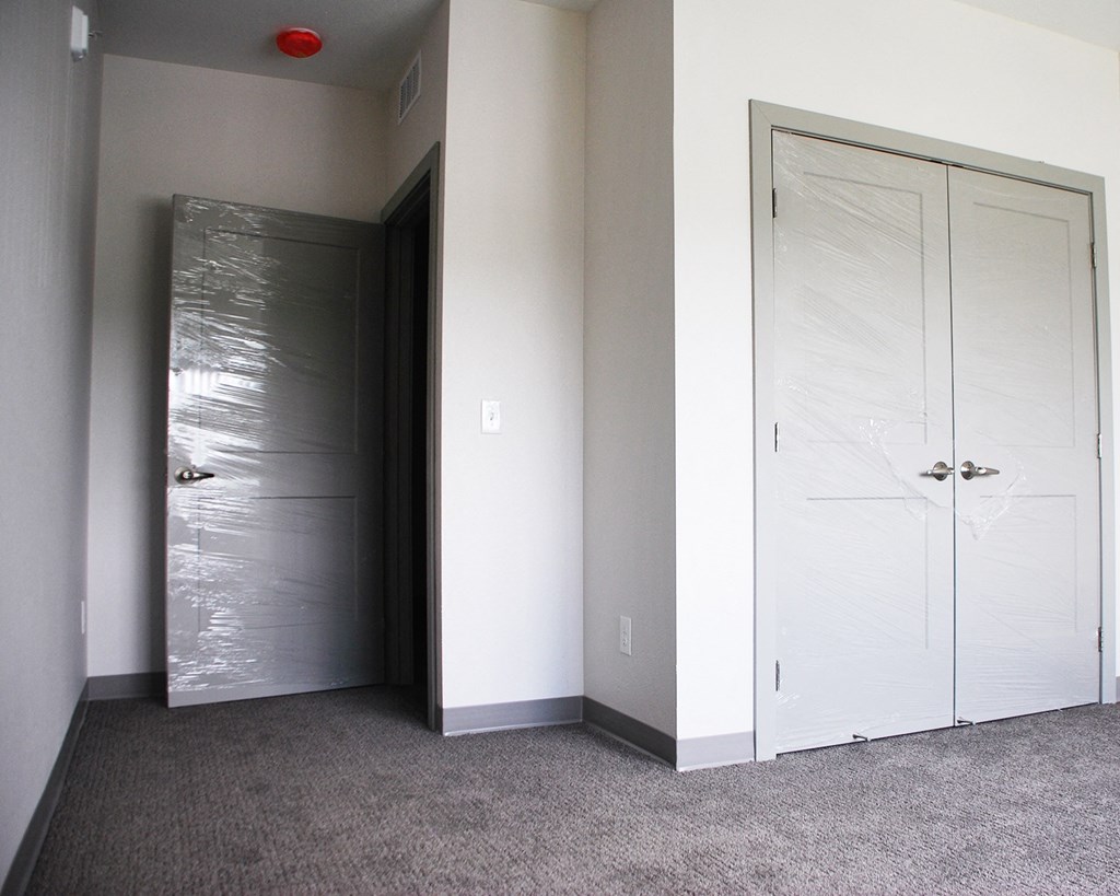 a pair of white doors in a room with a gray carpet