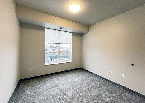 an empty living room with a large window and carpeting