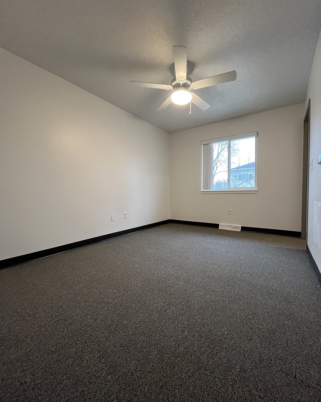 an empty living room with a ceiling fan and a window