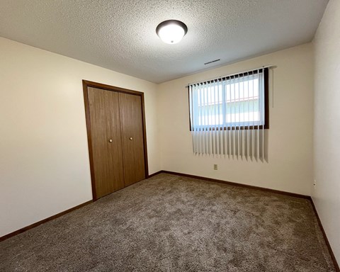 an empty living room with carpet and a window
