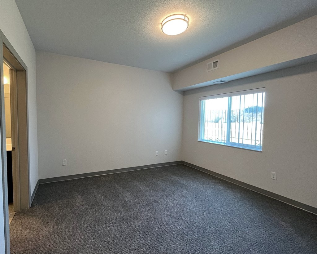 an empty living room with a window and carpet
