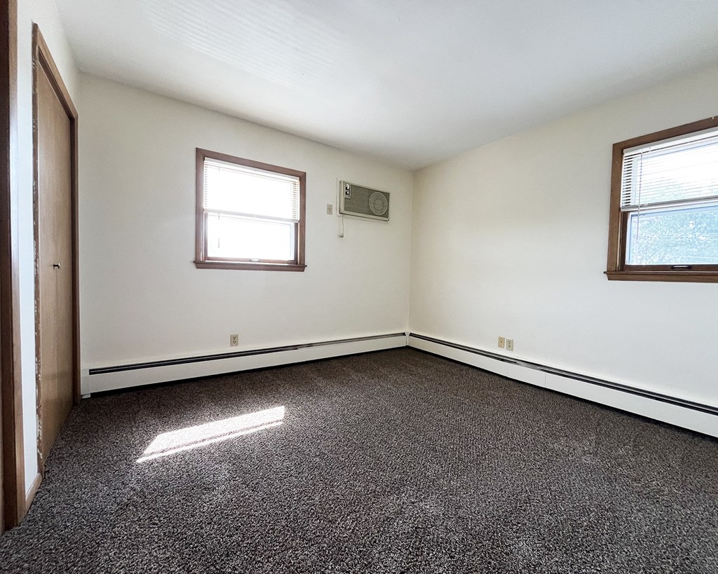 an empty room with a door and two windows