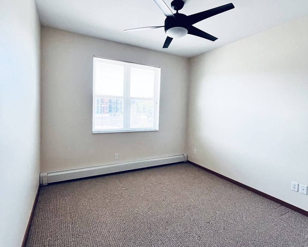 A room with a ceiling fan and a window.