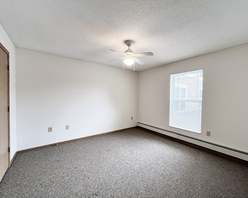 A room with a ceiling fan and a window with blinds.