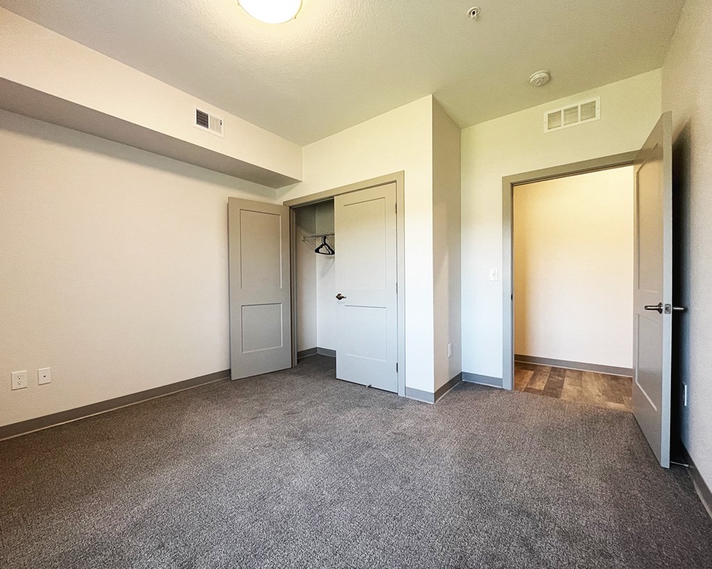 an empty living room with white walls and a door to a closet