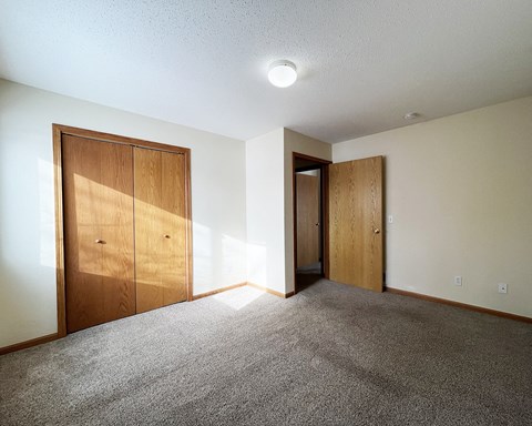 an empty living room with a door to a hallway and a closet