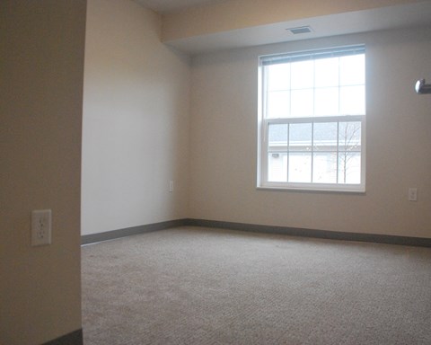 an empty living room with a window and carpet