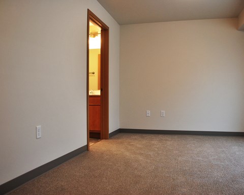 a room with a carpeted floor and a door to a bathroom