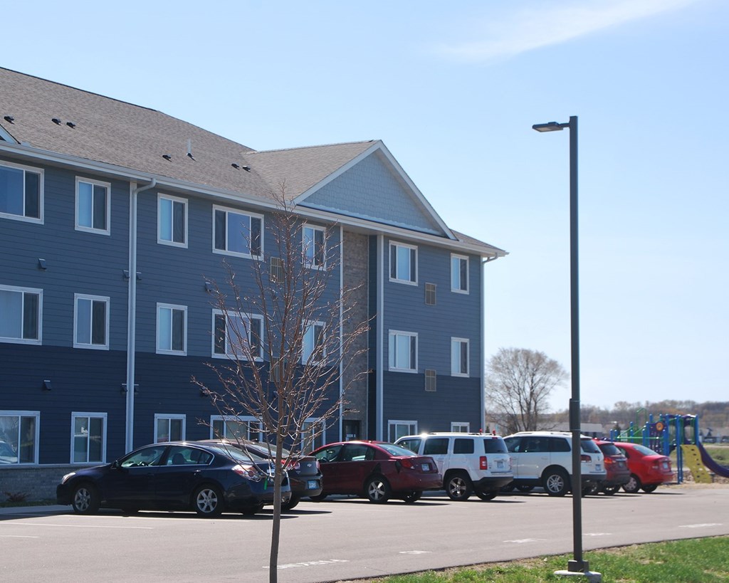 A black car is parked in front of a blue building.