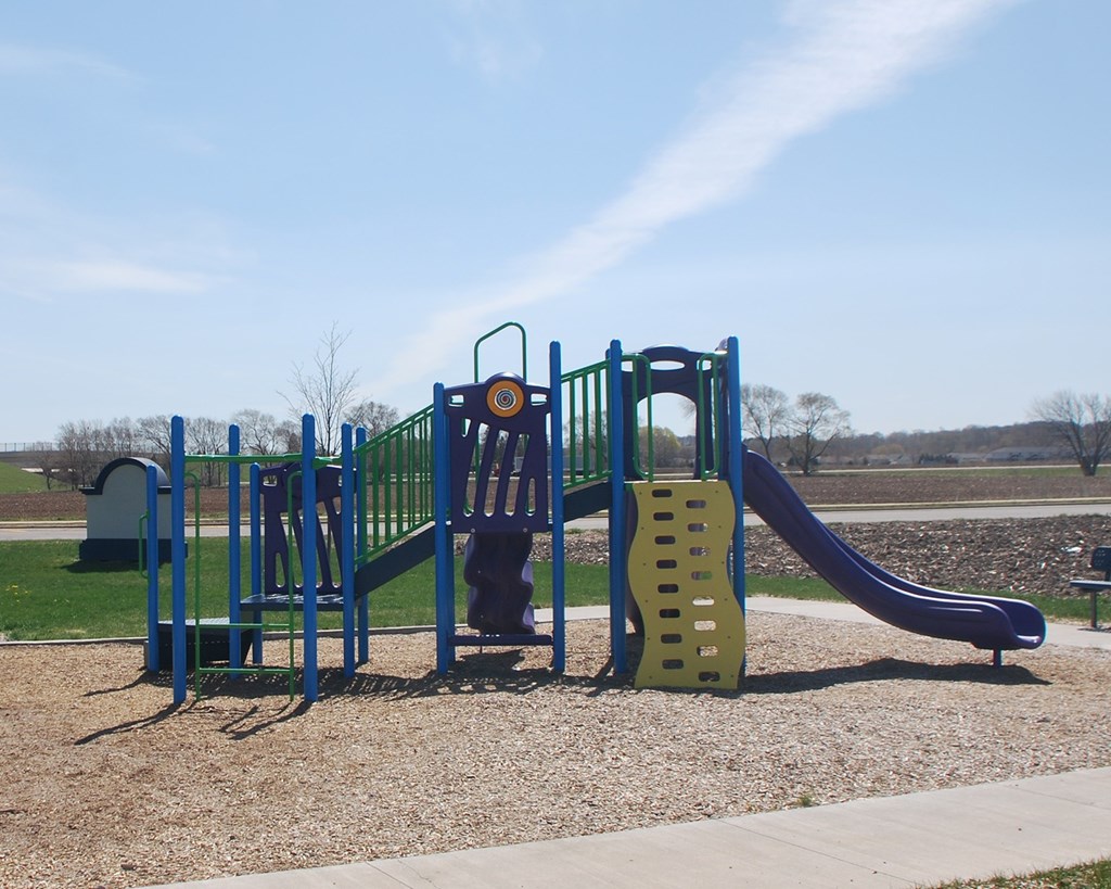 A playground with a blue and yellow slide and a purple slide.