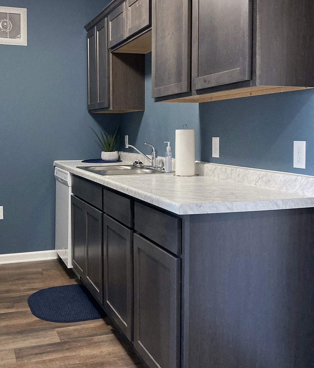 A kitchen with dark wood cabinets and a white counter.