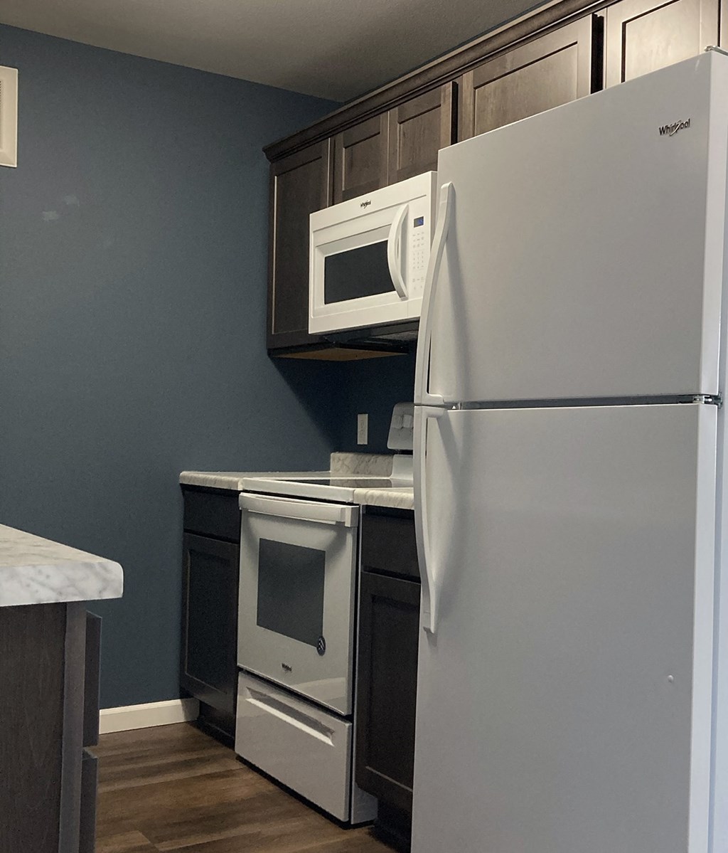 A white refrigerator is in a kitchen with a white countertop and a white oven.