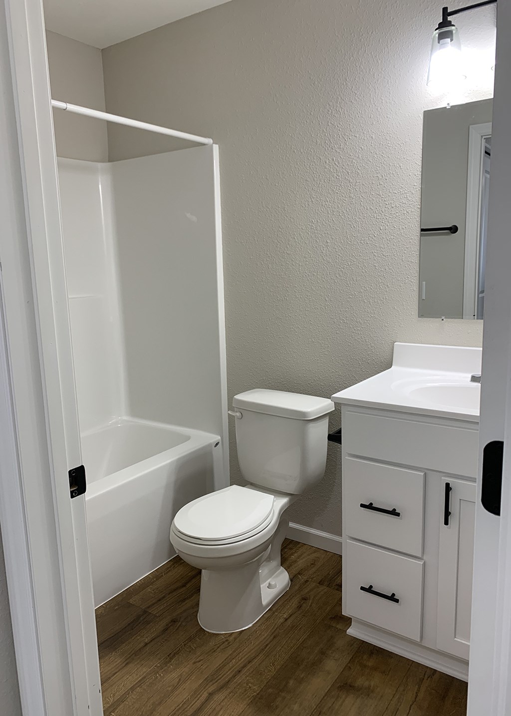 A white toilet in a small bathroom with a white sink and a white bathtub.