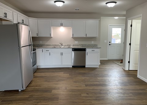 A kitchen with white cabinets and a wooden floor.