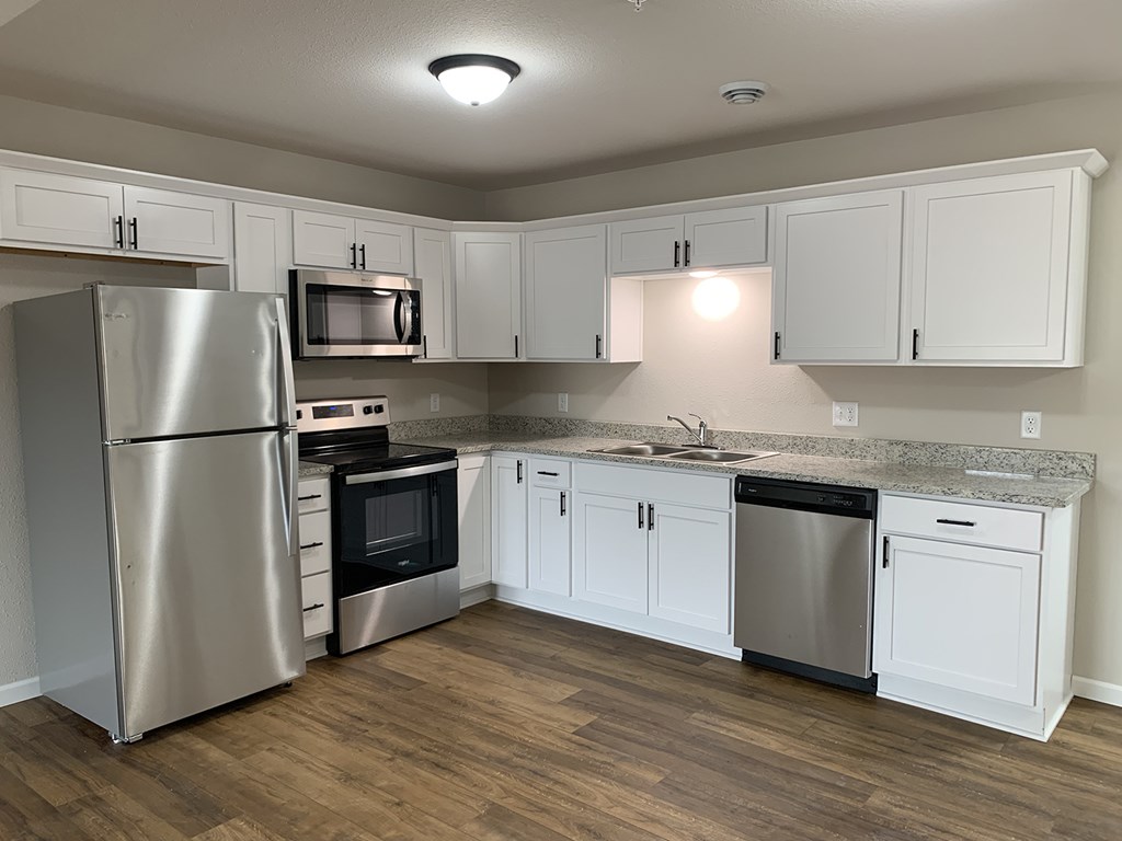 A kitchen with white cabinets and a granite countertop.