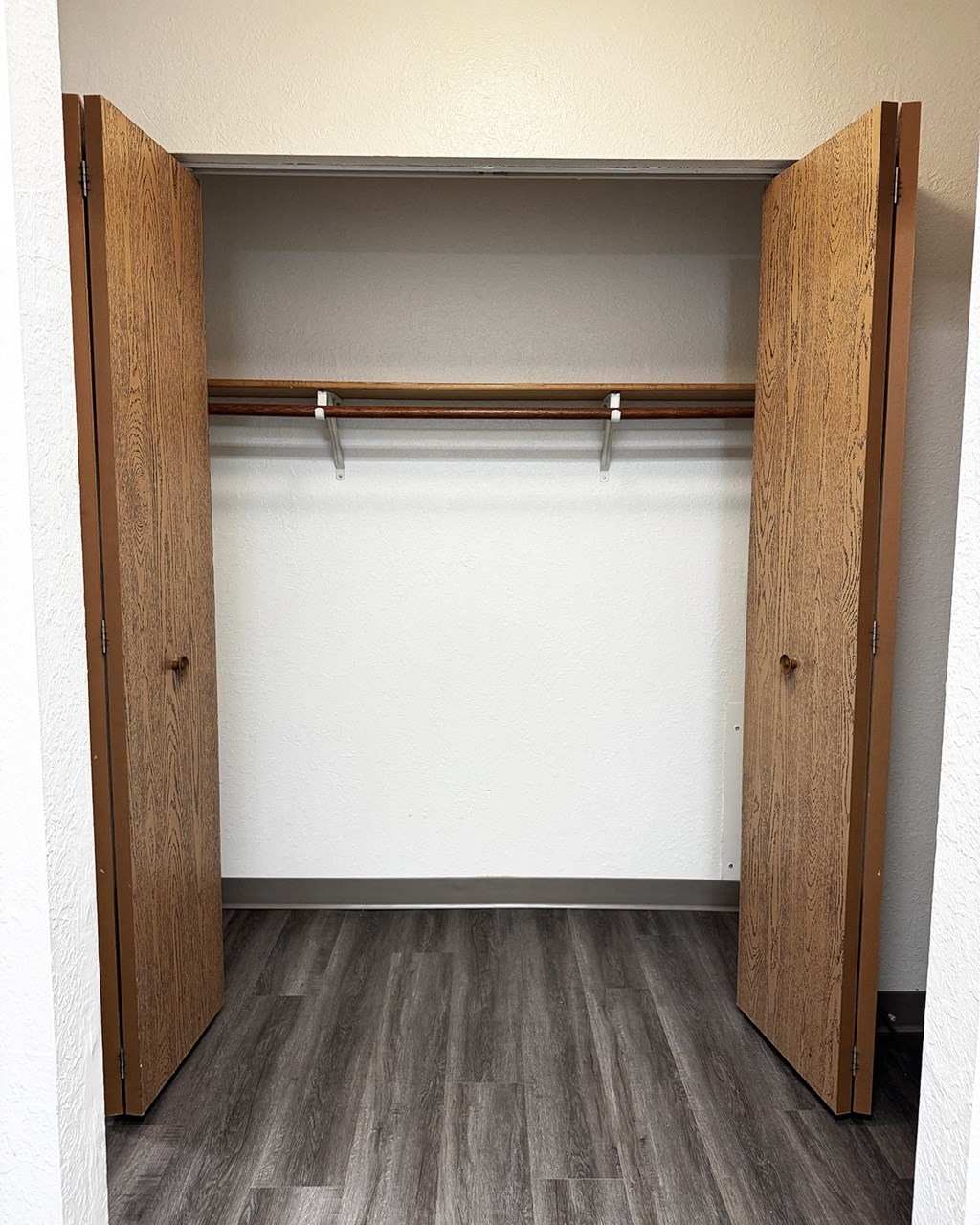 A wooden closet with a shelf and two doors.