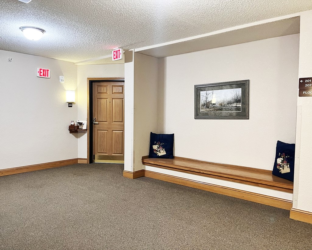 A hallway with a bench, a door, and a picture on the wall.