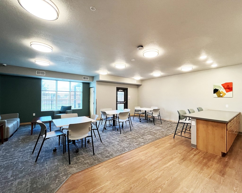 A room with tables and chairs and a green wall.