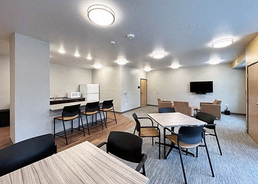 a community room with tables and chairs and a kitchen