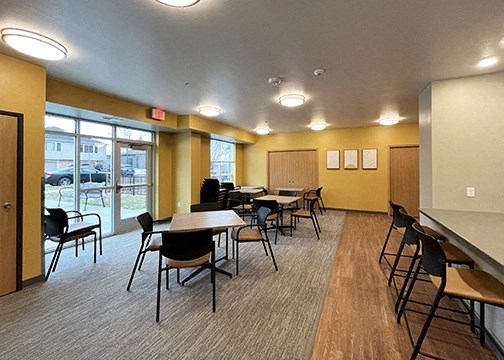 a community room with tables and chairs and a bar