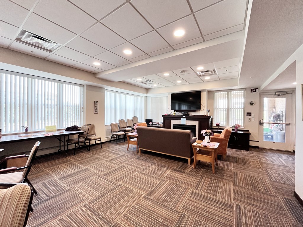 A conference room with a carpeted floor and a television mounted on the wall.