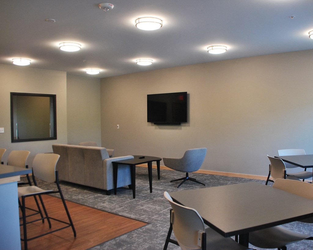 a room with a table and chairs and a television on the wall