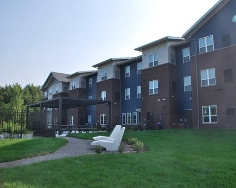 a large apartment building with a grassy yard and a lounge chair