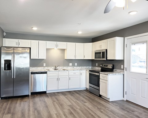 A kitchen with white cabinets and a wooden floor.