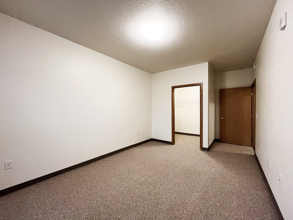 A room with a carpeted floor and a door on the right side.
