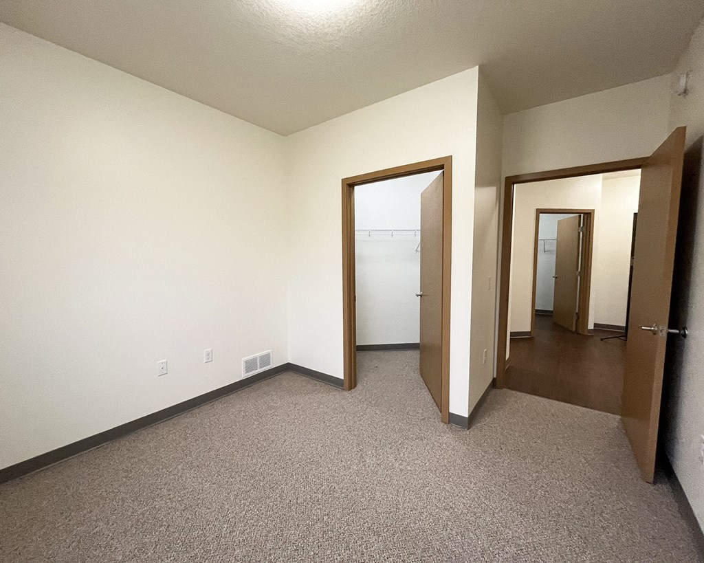 A room with carpeted floor and two open doors.
