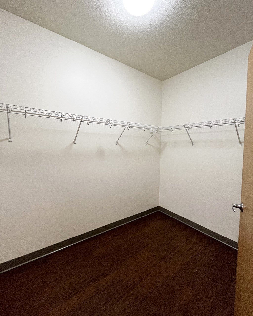 A white wall with a metal rack and a brown door.