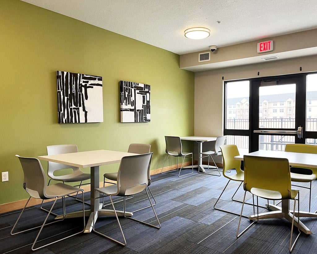 A room with a table and chairs and two framed pieces of art on the wall.